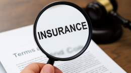 Close-up of a magnifying glass highlighting the word "insurance" on a document with a judge’s gavel in the background
