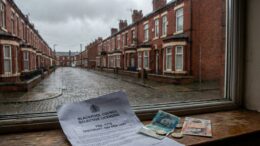 A rain-streaked terraced house in Blackpool with a council licensing document showing £772 fee and British banknotes on the s