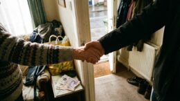 Landlord and tenants shaking hands at rental property doorway