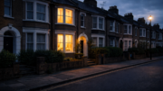 Moody dusk photograph of a British terraced street with one house warmly lit inside while neighbouring homes remain dark and unoccupied, illustrating uneven landlord profitability.