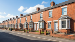 British terraced houses with For Sale sign on sunny street