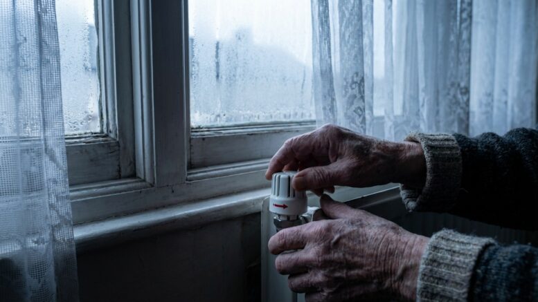 Older tenant adjusting heating in cold rental home