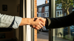 Landlord and tenant handshake at property doorway