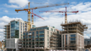 Cranes above modern UK apartment blocks on clear day