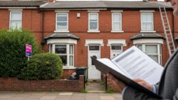 Man reviewing documents outside a terraced rental property