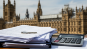 UK house purchase papers and calculator with Commons backdrop