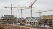 Scottish housing development with cranes under grey sky