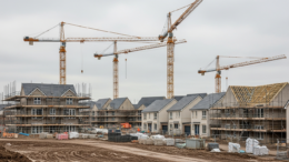 Scottish housing development with cranes under grey sky