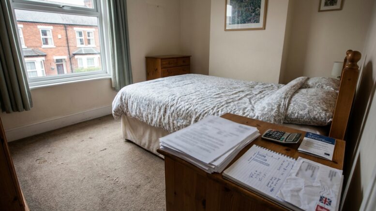 Spare bedroom prepared for a lodger with tax paperwork nearby