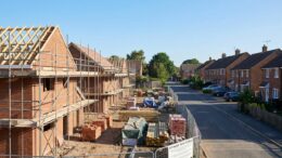 Half-built UK homes with scaffolding under clear blue sky