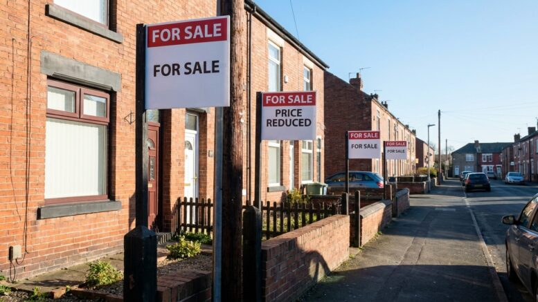 Terraced street with For Sale boards as price growth slows